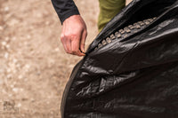 Loading bicycle into BikeParka RoughSac travel bag after outdoor ride